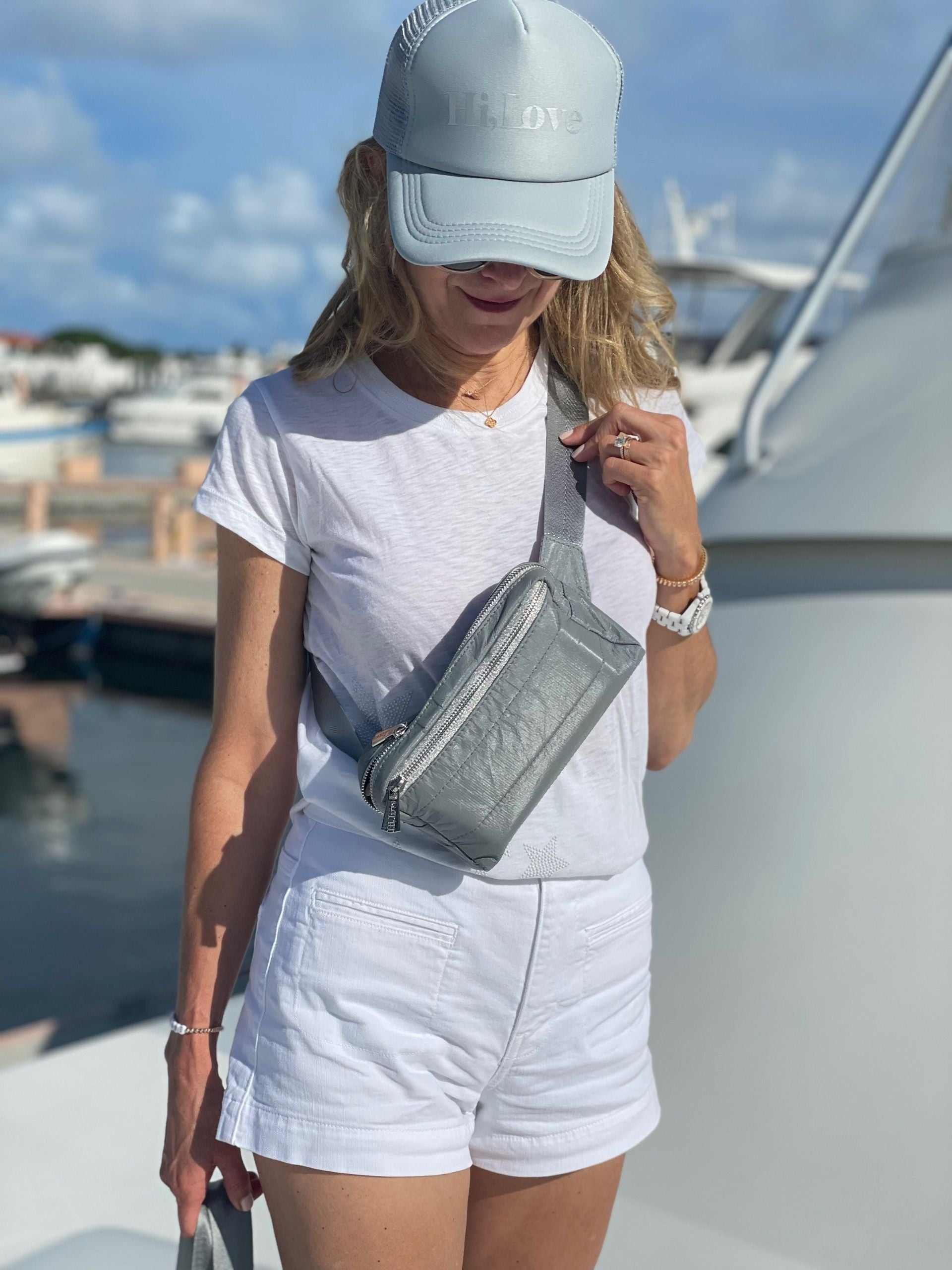 Woman on boat wearing Puffer Crossbody Fanny Pack Belt Bag in Shimmer Gray