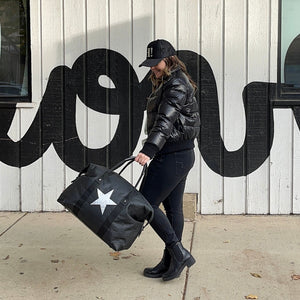 woman carries black duffle bag with silver star