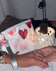 People holding hands wearing zip wristlet with pink hearts