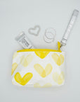 Yellow heart wristlet with earrings and hand cream on white background